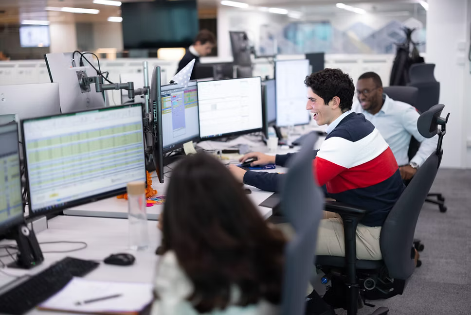 A trading team sharing a desk, mid-conversation.