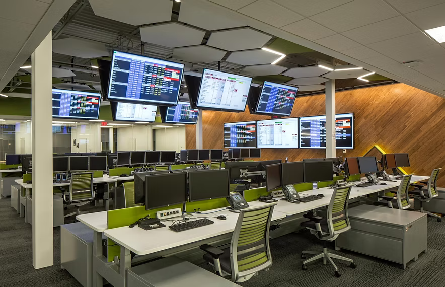 A modern energy trading room with overhead market screens and rows of desks.